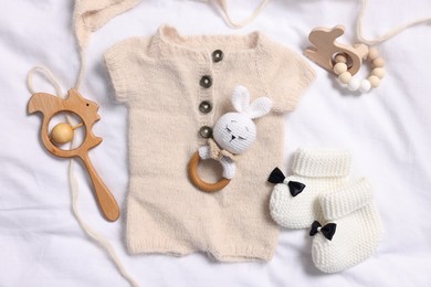 Different baby accessories on white fabric, flat lay