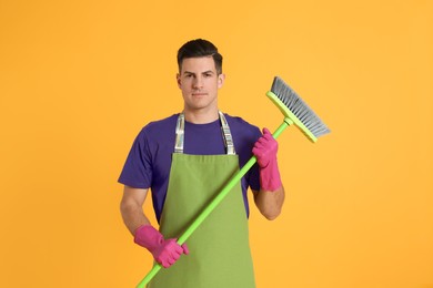 Photo of Man with green broom on orange background