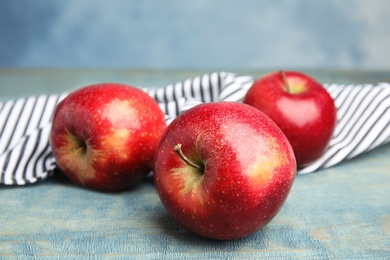 Photo of Ripe juicy red apples on wooden table against blue background, closeup