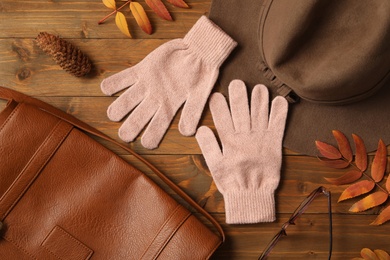 Photo of Flat lay composition with stylish pink woolen gloves and dry leaves on wooden table