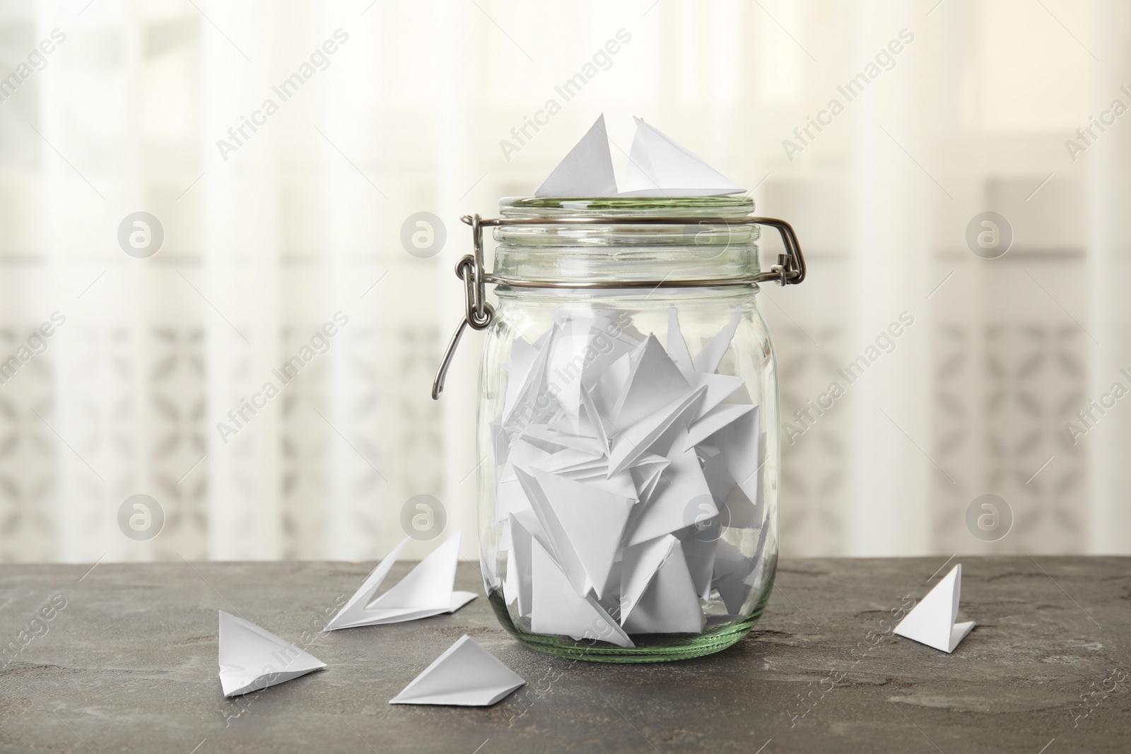 Photo of Paper pieces for lottery and glass jar on gray table