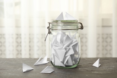 Paper pieces for lottery and glass jar on gray table