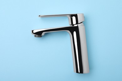 Photo of Single handle water tap on light blue background, top view