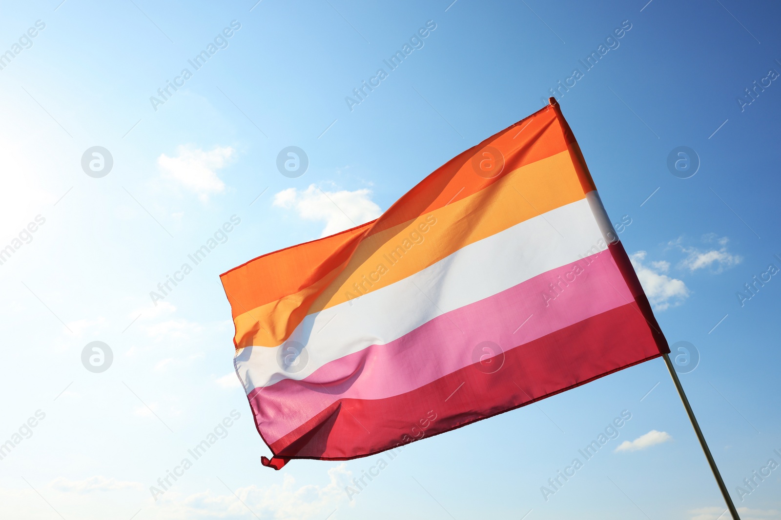 Photo of Bright lesbian flag fluttering against blue sky