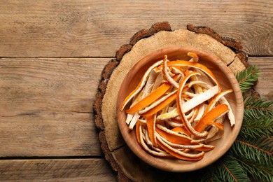 Photo of Dry orange peels and fir branches on wooden table, flat lay. Space for text