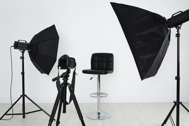 Photo of Empty chair in front of camera and professional lighting equipment indoors. Photo studio set