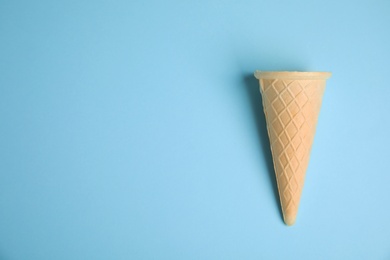 Empty wafer ice cream cone on blue background, top view. Space for text