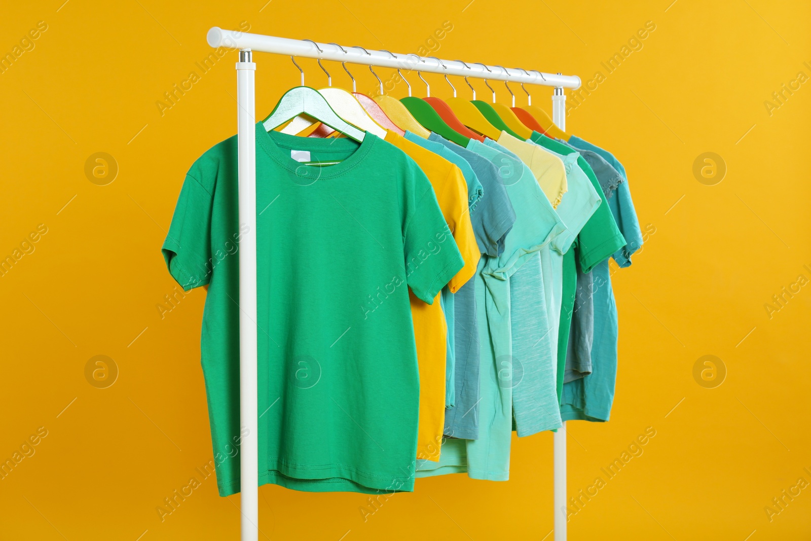 Photo of Rack with stylish children clothes on yellow background