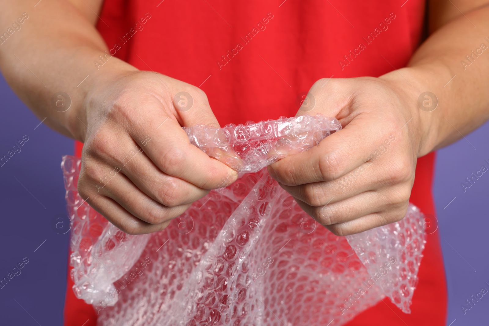 Photo of Man with bubble wrap on purple background, closeup