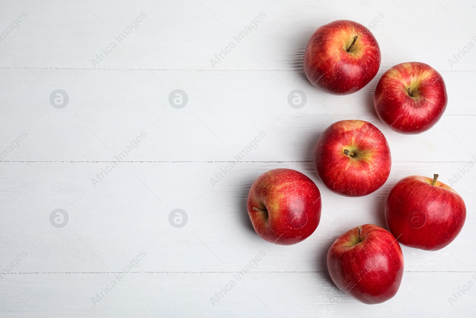 Photo of Ripe red apples on white wooden table, flat lay. Space for text