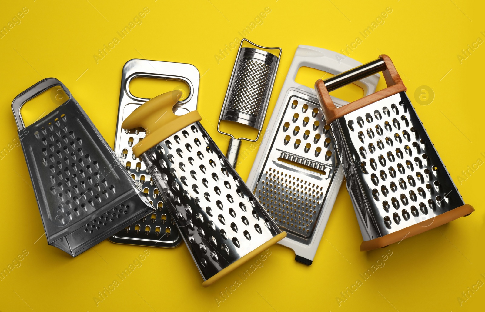 Photo of Different modern graters on yellow background, flat lay