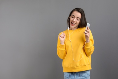 Photo of Young woman using phone for listening to music against color background