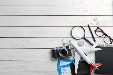 Photo of Flat lay composition with toy airplane and travel items on white wooden background. Space for text