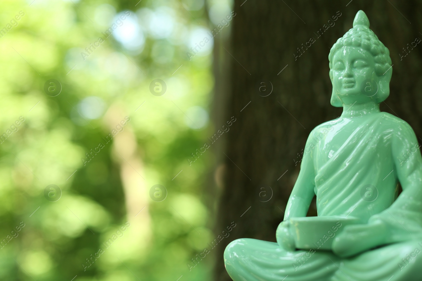 Photo of Decorative Buddha statue on blurred background, closeup. Space for text