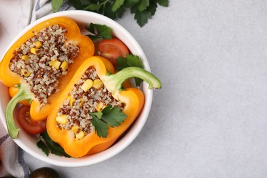 Photo of Quinoa stuffed bell pepper, tomatoes and parsley in bowl on light table, top view. Space for text