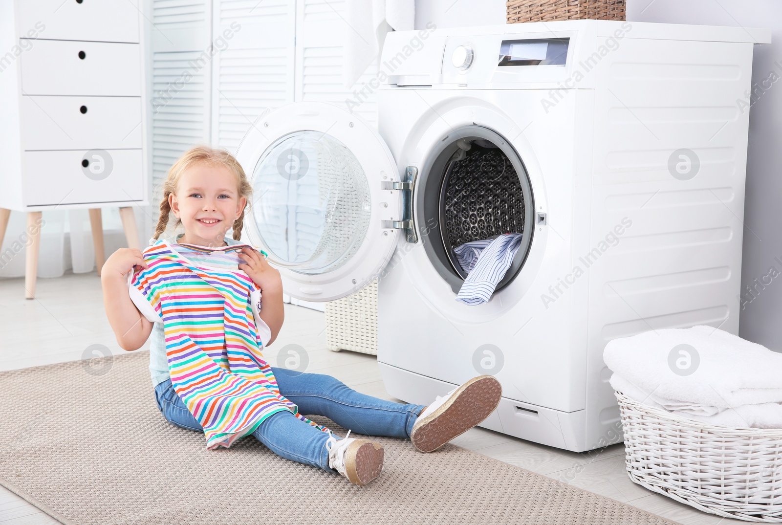 Photo of Adorable little girl doing laundry at home