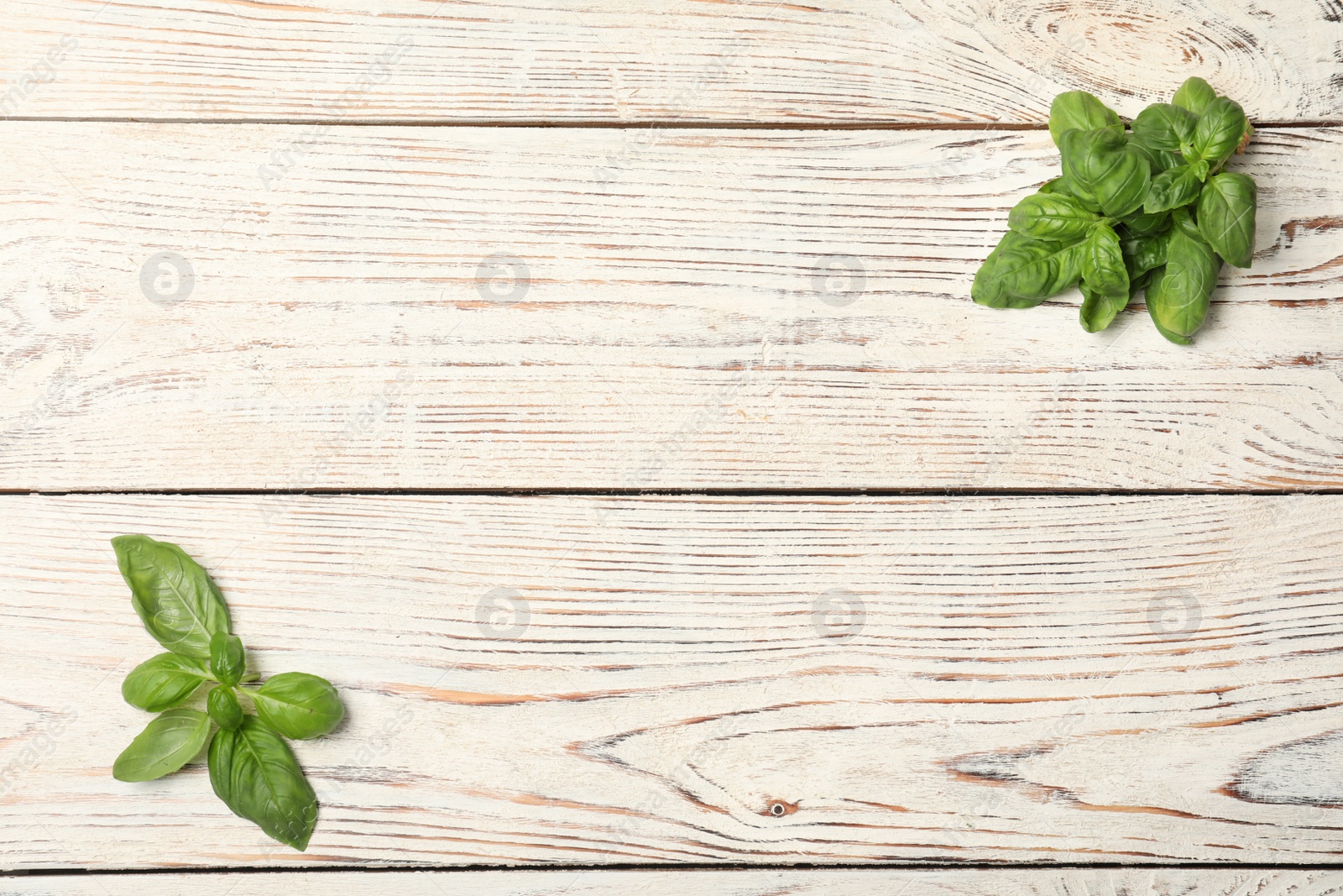 Photo of Fresh basil leaves on wooden background, top view. Space for text