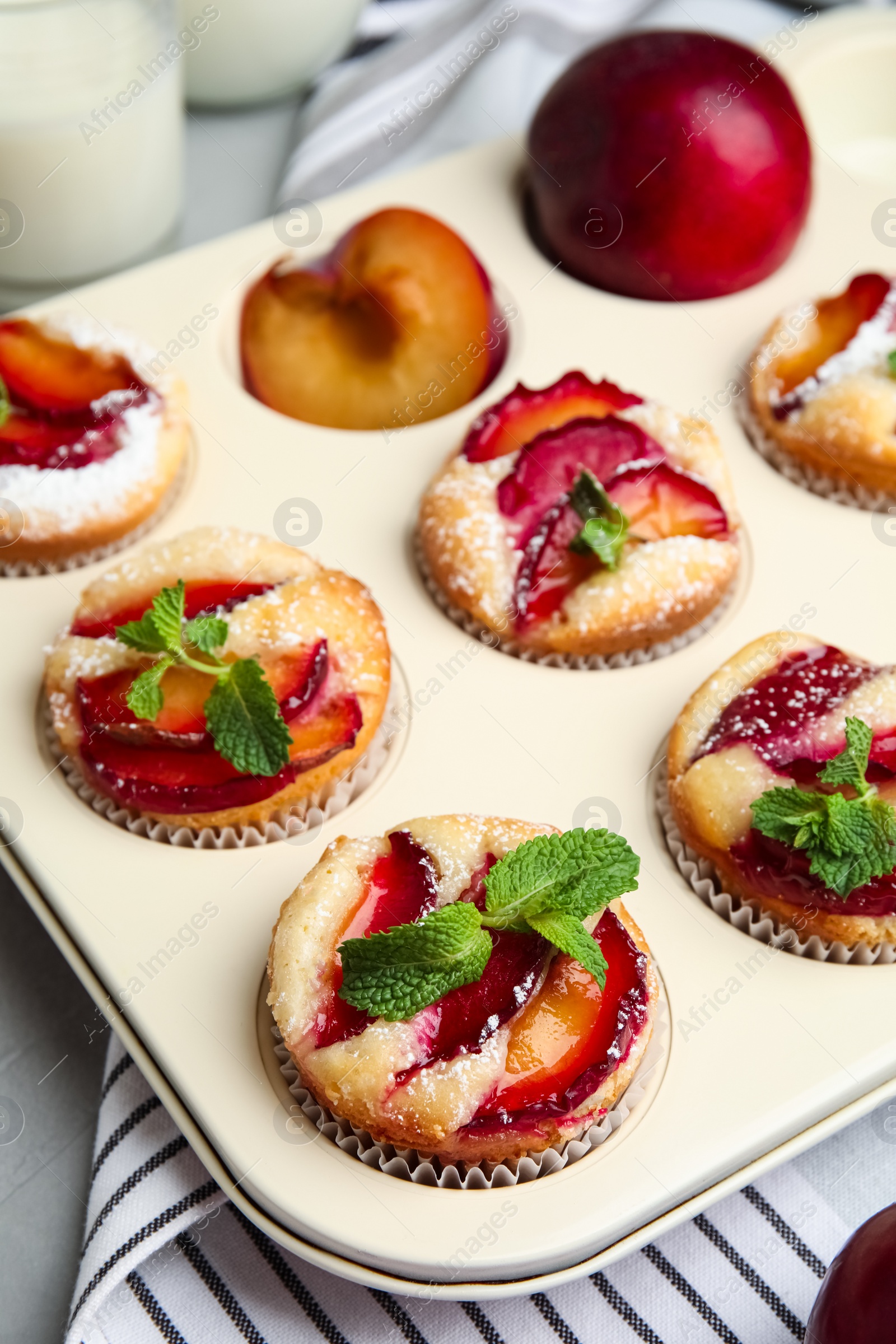 Photo of Delicious cupcakes with plums in baking pan