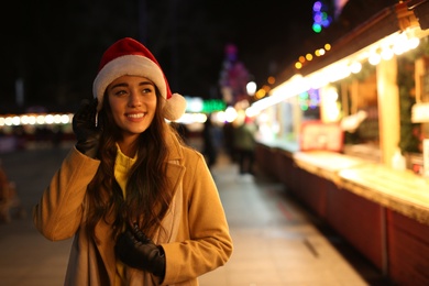 Young woman spending time at Christmas fair, space for text