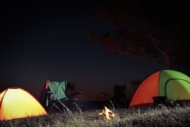Photo of Camping tents and chairs in wilderness at night