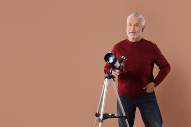 Photo of Senior astronomer with telescope on brown background. Space for text