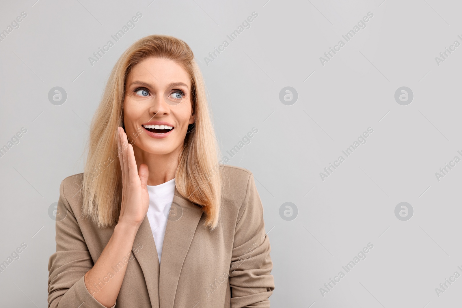 Photo of Portrait of surprised middle aged businesswoman on light grey background. Space for text