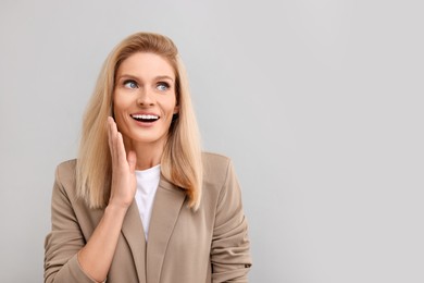 Photo of Portrait of surprised middle aged businesswoman on light grey background. Space for text