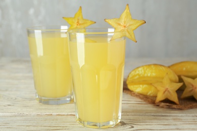 Photo of Delicious carambola juice and fresh fruits on wooden table