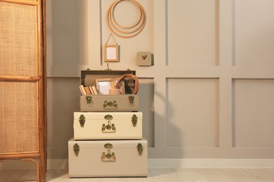 Photo of Storage trunks with different decor elements near light wall indoors, space for text. Interior design