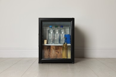 Mini bar filled with food and drinks near white wall indoors