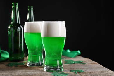 Photo of St. Patrick's day party. Green beer and decorative clover leaves on wooden table. Space for text