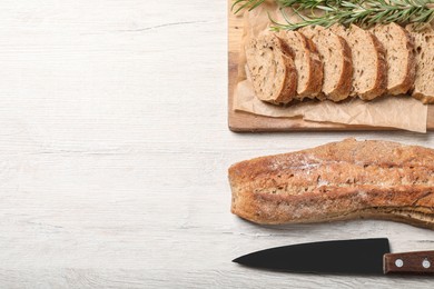 Buckwheat baguettes with knife and rosemary on white wooden table, flat lay. Space for text