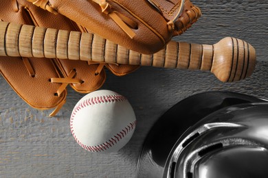 Photo of Baseball glove, bat, ball and batting helmet on grey wooden table, flat lay