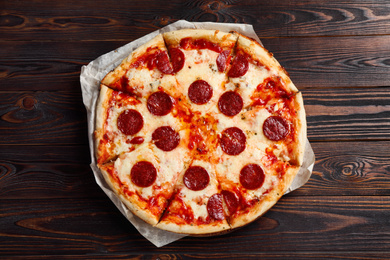 Photo of Hot delicious pepperoni pizza on wooden table, top view