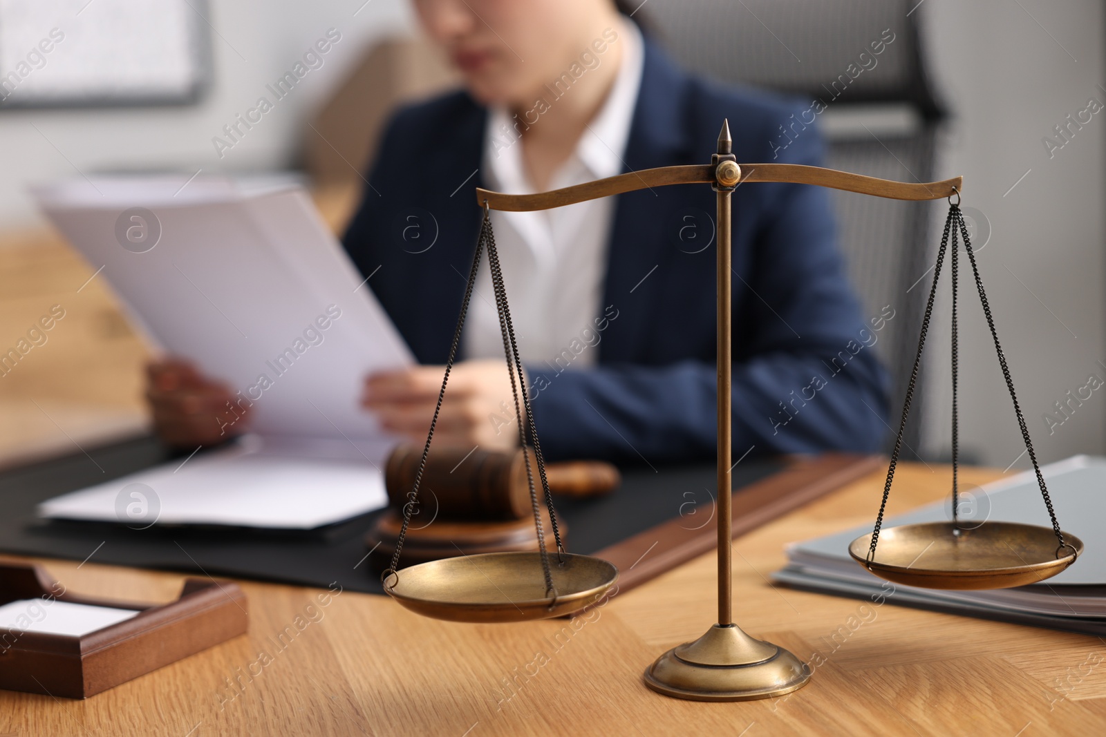 Photo of Notary reading document at table in office, focus on scales