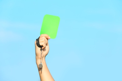 Photo of Football referee showing green card against blue sky, closeup with space for text