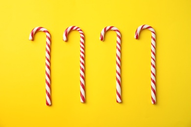 Photo of Flat lay composition with candy canes on yellow background