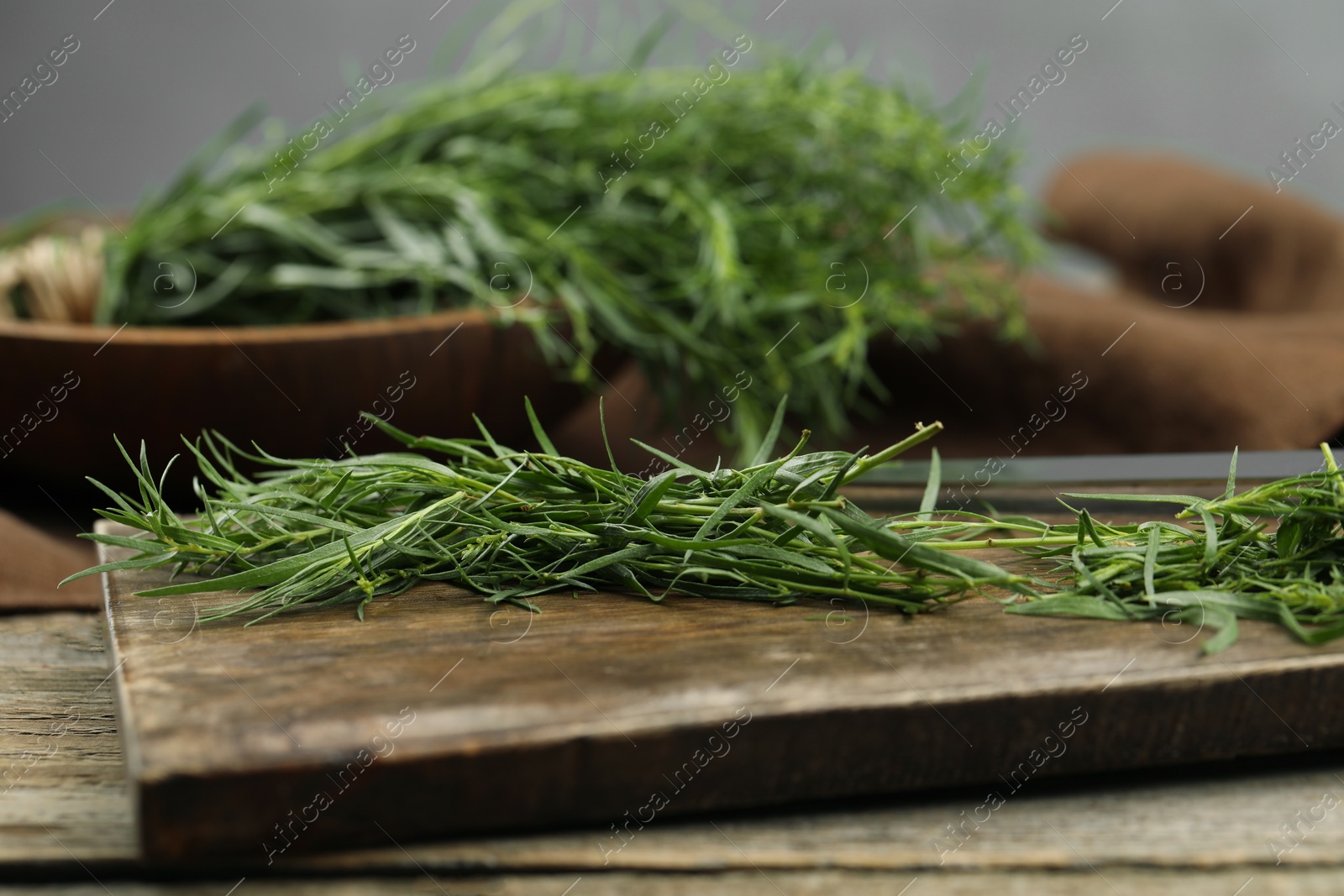 Photo of Fresh tarragon sprigs on wooden table, closeup