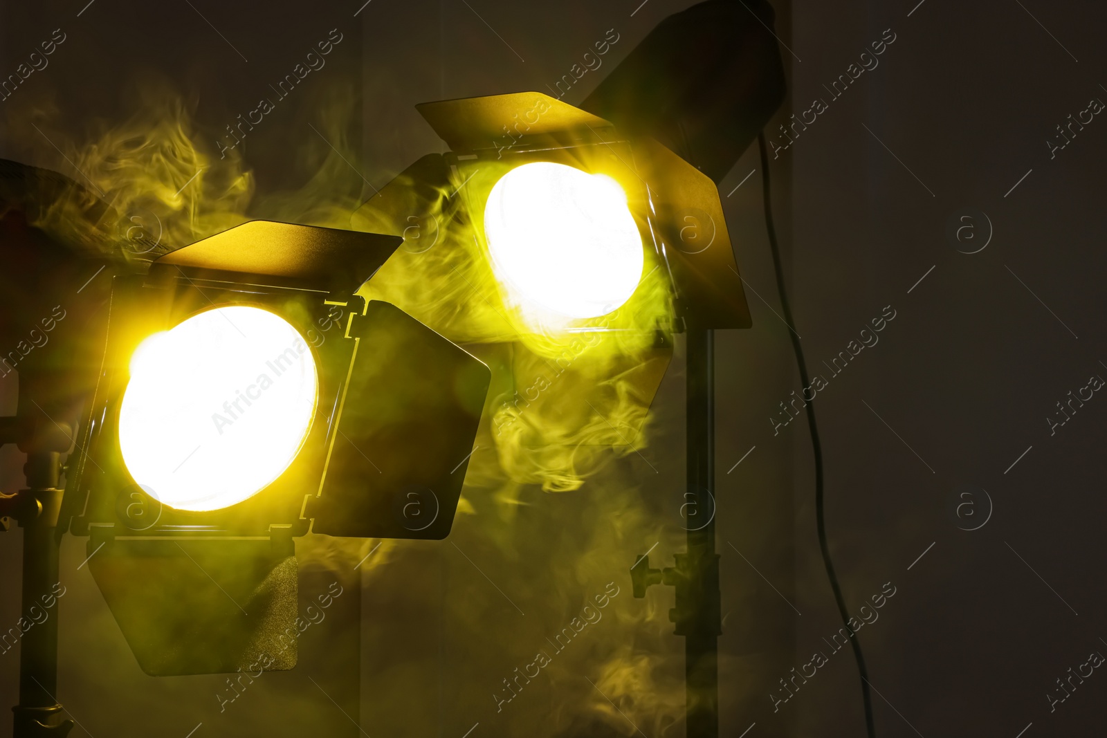 Photo of Bright yellow spotlights near wall indoors. Professional stage equipment