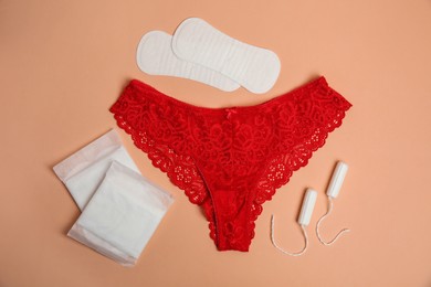 Photo of Flat lay composition with woman's underwear and menstrual pads on pale orange background. Gynecological care