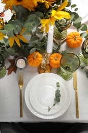 Beautiful autumn table setting. Plates, cutlery, glasses, pumpkins and floral decor, flat lay