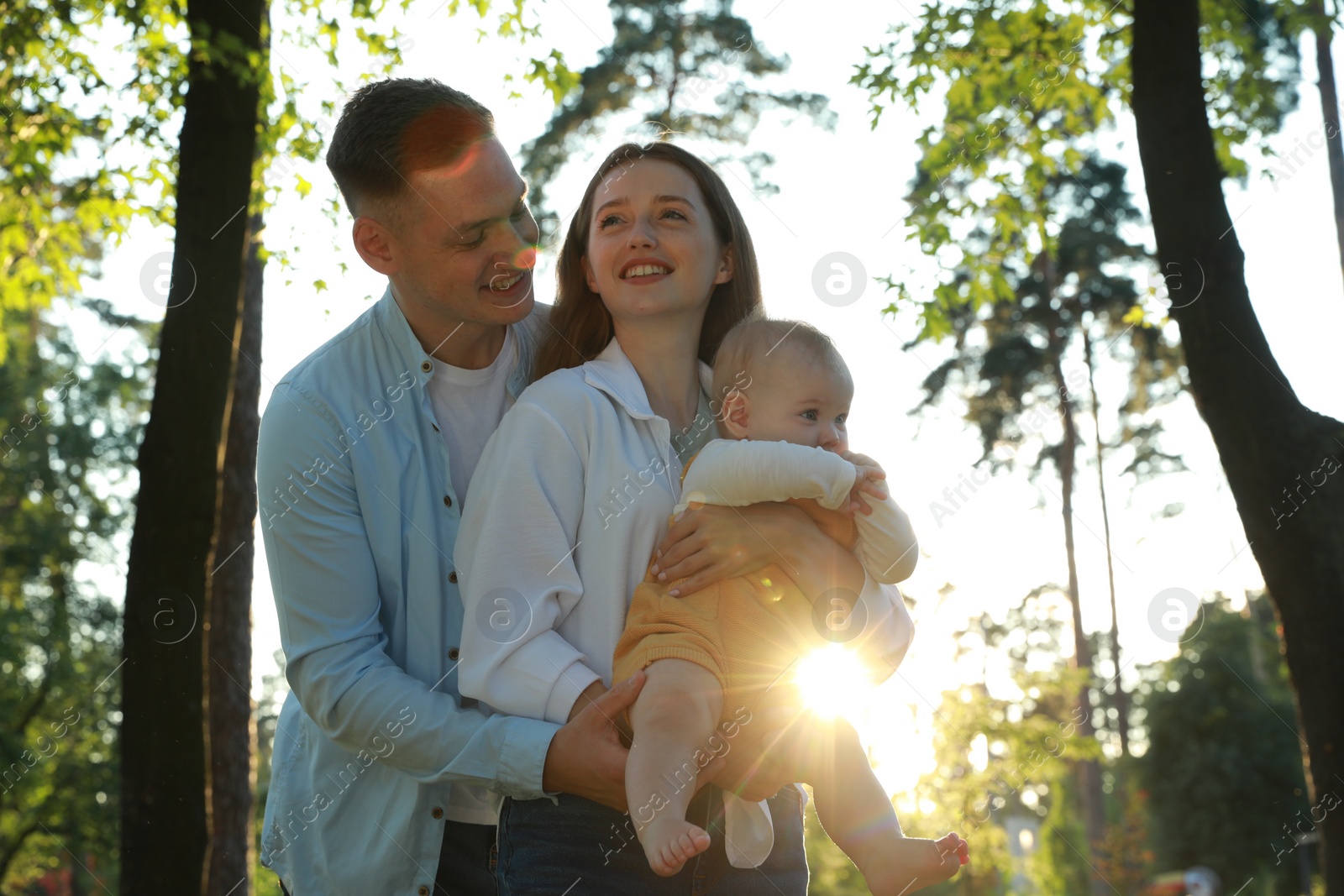 Photo of Parents with their cute daughter spending time together in park on summer day