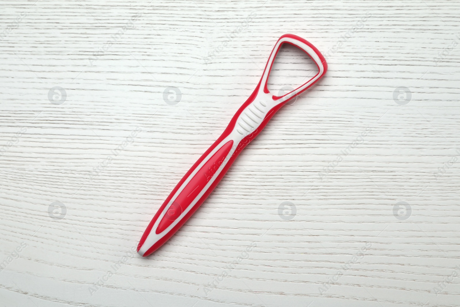 Photo of Red tongue cleaner on white wooden table, top view