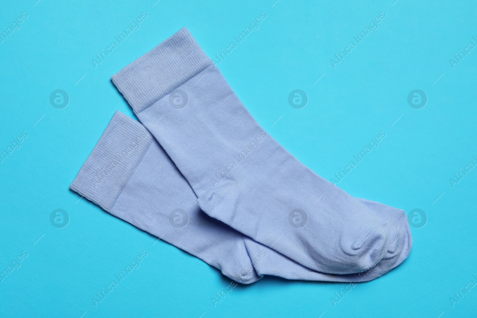 Photo of Pair of new socks on light blue background, flat lay