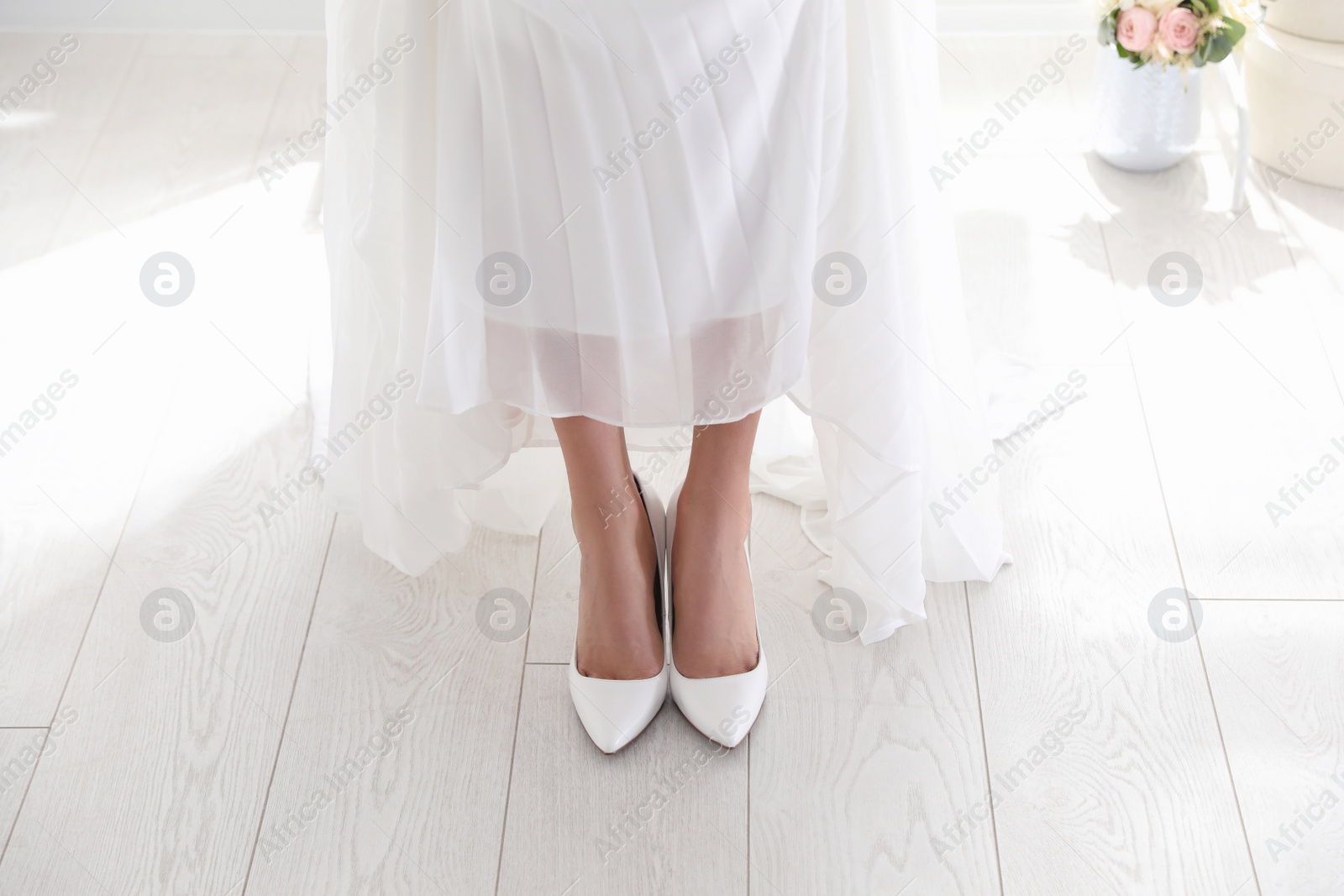 Photo of Young bride wearing beautiful wedding shoes indoors, closeup