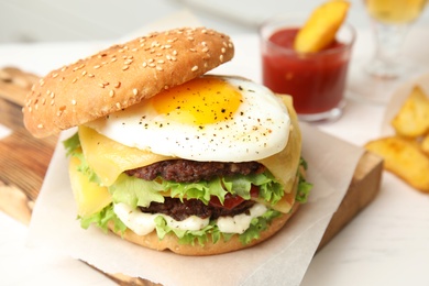 Photo of Tasty burger with fried egg on wooden board