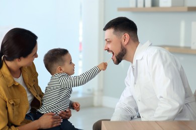 Photo of Mother and son visiting pediatrician in hospital. Doctor playing with little boy