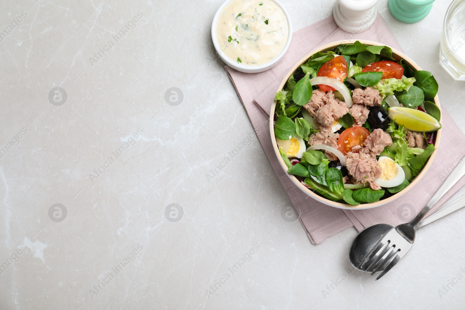 Photo of Bowl of delicious salad with canned tuna and vegetables served on light table, flat lay. Space for text