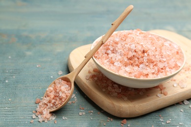 Photo of Pink himalayan salt on light blue wooden table, closeup