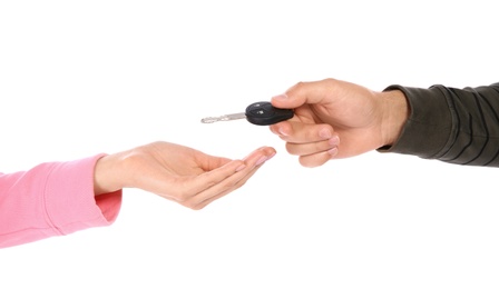 Photo of Agent giving car key to woman on white background, closeup. Getting driving license